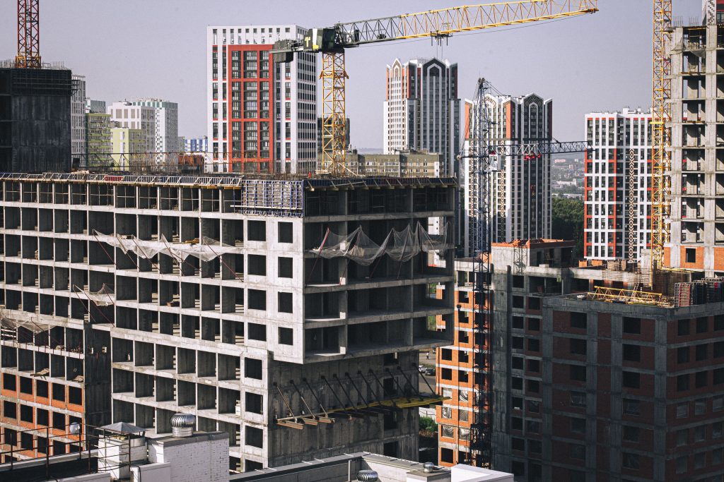 High-rise buildings under construction with tower cranes in a cityscape.